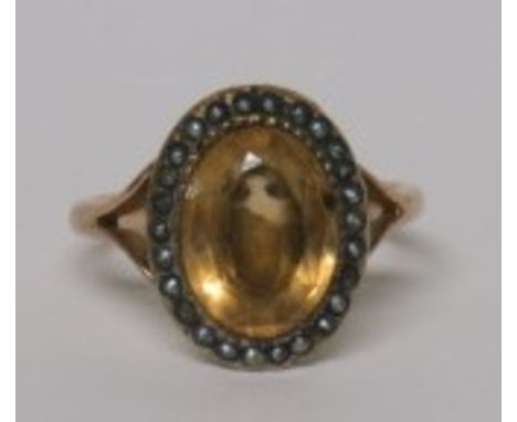 An oval faceted lemon citrine cocktail ring with a seed pearl surround on an unmarked gold (tested) shank, ring size M 1/2, w
