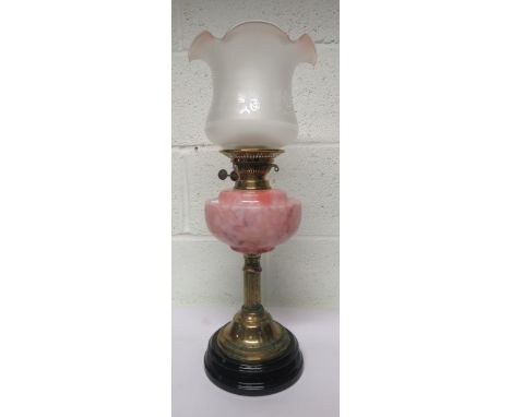 Brass oil lamp with column support, with a pink glass reservoir and together with a chimney and a clear glass shade with flor