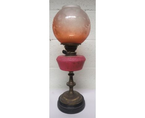 Victorian brass oil lamp with a pink glass reservoir and a dark orange shade, with floral decoration, 56cm high