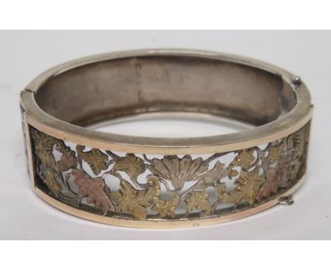 A Victorian silver bangle with an openwork front panel of gilt carved leaves, the bangle is hallmarked for Birmingham, 1883, 