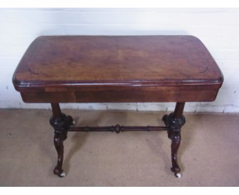 A 19th century walnut and inlaid card table of serpentine outline baize lined folding and swivel top on turned and carved end