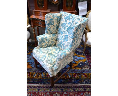 A 19th century mahogany framed wingback armchair, green and beige floral and foliate upholstery with a matching seat cushion,