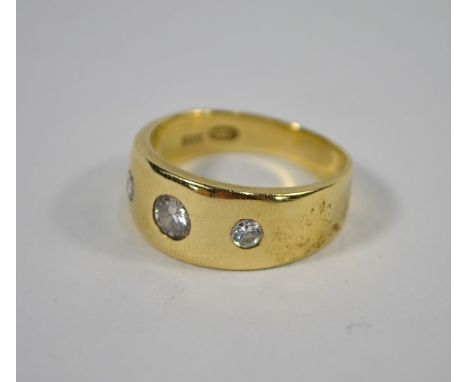 A yellow metal wide band set with three gypsy set brilliant cut graduated diamonds, stamped 585, approx 8.8g all in, size R