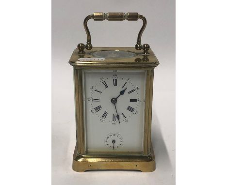 A small early 20th century lacquered brass carriage alarm clock, with white enamelled dial, striking on a bell, 12 cm h