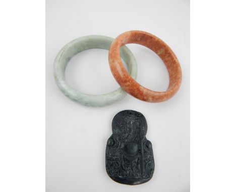 Two jade bracelets, and a spinach jade pendant of a seated war lord, 5.4cm. (3)
