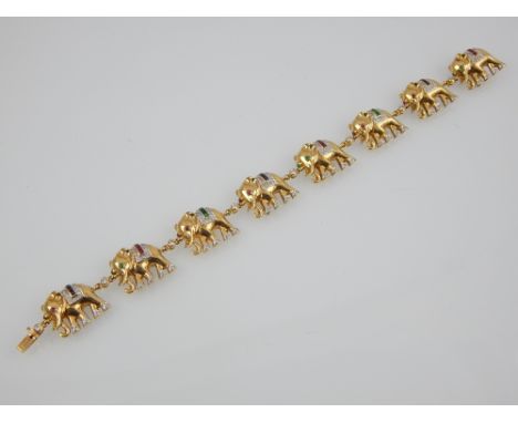 A diamond, ruby, emerald and sapphire set bracelet in 18ct yellow. Each link formed as an elephant with a bejewelled eye, fee