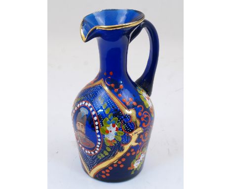 A Bohemian blue glass jug, 19th century, the body enamelled and gilded with foliate motifs and cartouches, featuring an oval 