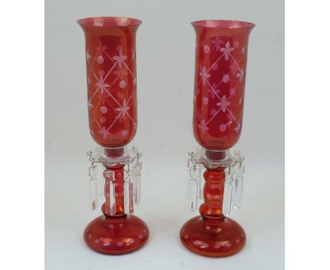 A pair of cranberry glass lustre candlestick lamps, 20th century, with clear glass sconces and faceted drops, some missing, t