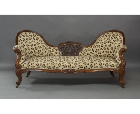 A Victorian mahogany spoon back sofa, the central carved and pierced floral decoration and carved frame, with recent leopard 