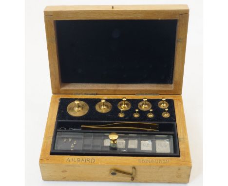 A set of brass jewellers' weights, held in a fitted wood case with a pair of tweezers, the case inscribed 'A.H.BAIRD EDINBURG