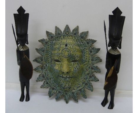 A pair of 1950's carved African tribesman in ebony and a ceramic face mask wall plaque, height of figures 32cm