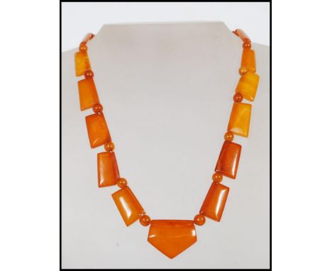 A vintage Art Deco amber bakelite necklace with yellow metal clasp. Large axe shaped panels with smaller bead spacers.