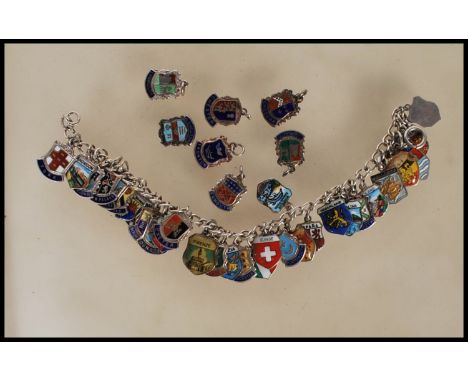 A vintage sterling silver souvenir / charm bracelet having a large number of silver enamelled shields from around the UK and 