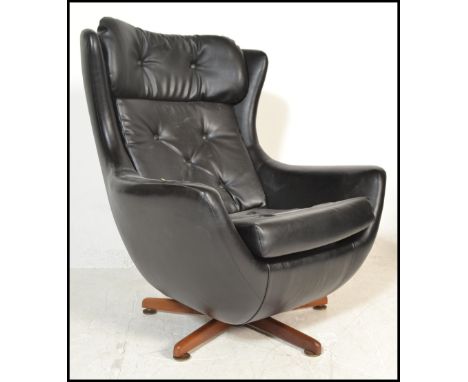 A 1970's retro vintage Parker Knoll statesman swivel and tilt action egg chair having a black leather vinyl upholstery with b