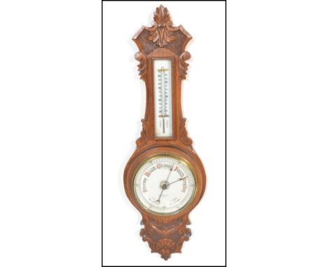 An early 20th Century 1930's oak cased Aneroid barometer having carved floral work to case. Set with a white ceramic dial wit