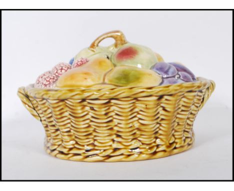 An early 20th Century ceramic Sarreguemines lidded pot modelled as a basket of fruit, the base formed as a wicker basket and 