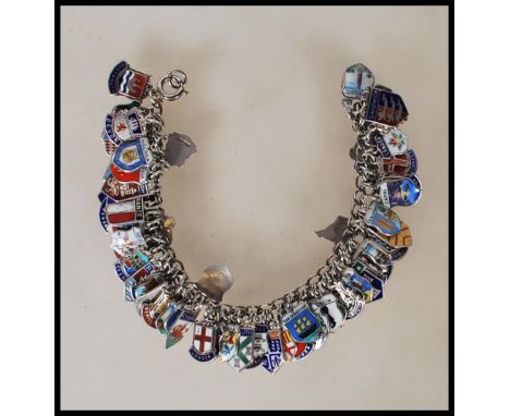 A vintage sterling silver souvenir / charm bracelet having a large number of silver enamelled shields from around the UK and 