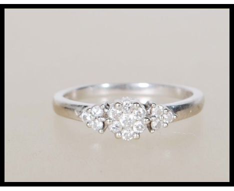 A hallmarked 9ct white gold ring set with a central cluster of white stones flanked by three further white stones to either s