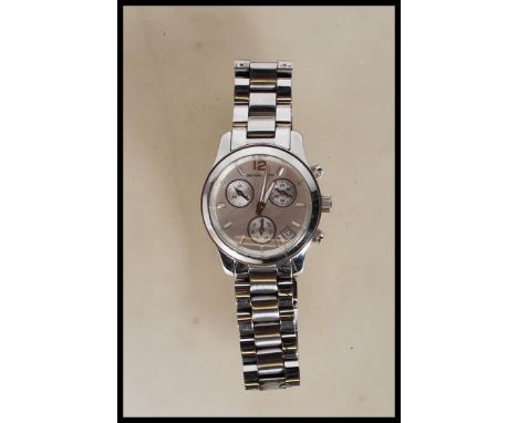 A contemporary ladies Michael Kors wrist watch having a round face with a silvered dial with baton markings to the chapter ri