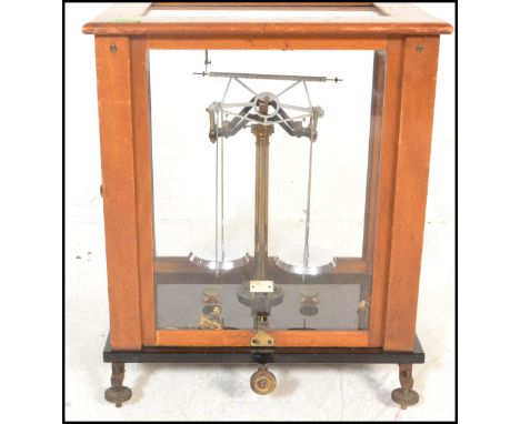 An early 20th Century&nbsp;wooden cased scientific scales in brass set to a black glass base with adjustable feet. dimensions