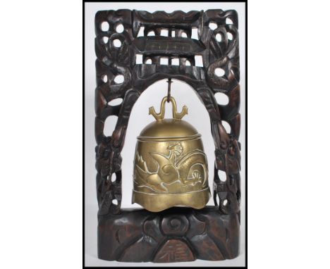 A 20th Century carved Chinese hardwood table top bell having a large carved wood pierced decoration stand with silver wire in