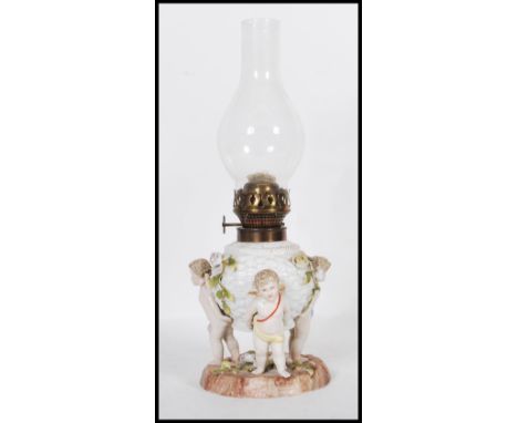 A 19th Century German Sitzendorf floral encrusted winged cherub / putti porcelain oil lamp set over a floral spray embellishe