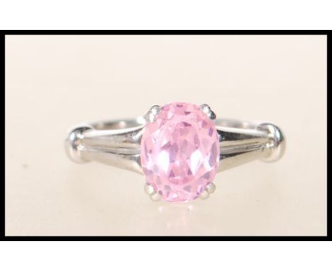 A stamped 9k 375 white gold single stone dress ring having central faceted prong set pink stone with decorative shoulders. We