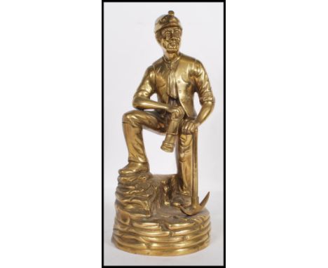 A vintage mid-20th century brass statue of a coal miner. Depicted in full mining gear, complete with lamp and pickaxe. Measur