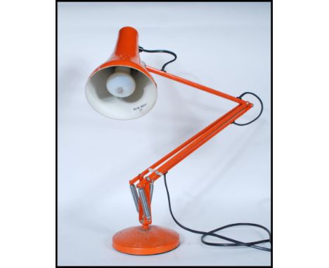 A vintage 20th Century Herbert Terry Industrial anglepoise desk lamp in an orange colourway, raised on circular base with adj