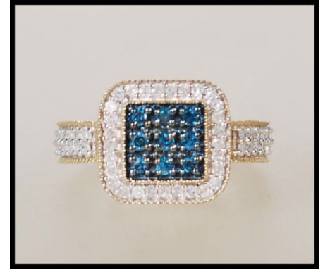 A hallmarked 9ct gold dress ring having a square head set with a square cluster of blue stones having white accent stones sur