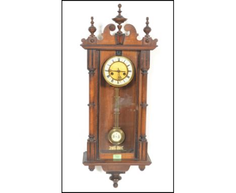 A 20th Century spring driven eight day wall hanging Vienna regulator, the walnut case surmounted by brass finials, enamel dia