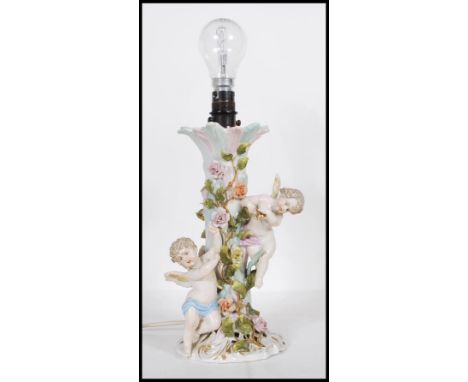 A 20th Century German porcelain Sitzendorf table lamp encrusted with florals and winged cherubs, one holding a gilt bell. Sit