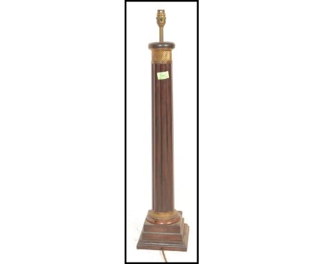 An early 20th Century mahogany table lamp having a reeded column with a gilt twist design panel to the top, being raised on a