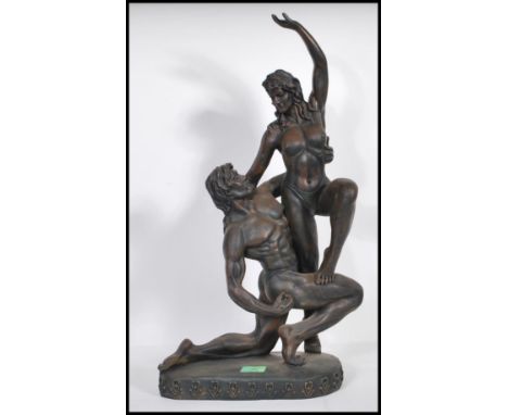 Two contemporary composite figurines of naked lovers, the first of a naked female held aloft raised on a natural plinth base 