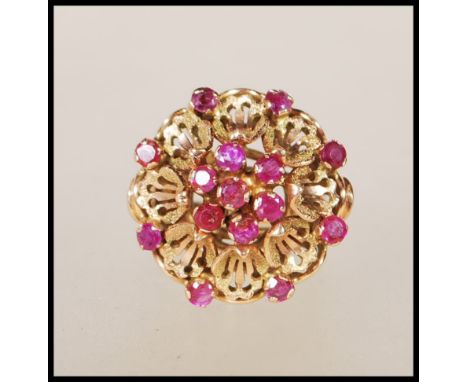 A stamped 14ct gold ladies dress ring having a round flower head with applied pierced decoration petals, set with round cut r