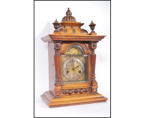 A late 19th / early 20th Century walnut cased brass faced eight day mantel clock, the case of architectural form, brass face 