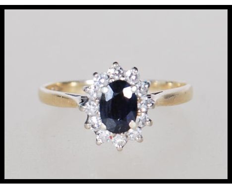 A hallmarked 9ct gold ring set with an oval cut sapphire with a halo of white stones. Hallmarked London 1985. Weight 1.7g. Si