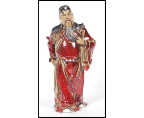 A stoneware figure of Chinese warrior decorated with&nbsp;sang de boeuf glaze with light green highlights. Measures 32cm tall