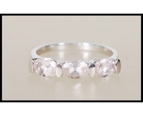 A hallmarked 9ct white gold ring set with three oval cut pink stones. Hallmarks for Birmingham 375. Weighs 2.3g. Ring size O