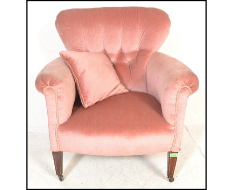 An early 20th century button back Edwardian scroll arm armchair. Standing on squared tapering supports terminating on ceramic