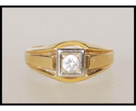 A stamped 750 18ct gold signet ring set with a round cut white stone within a white gold square head on reeded shoulders. Wei