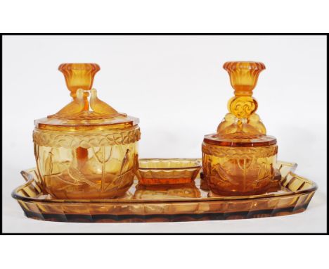 An early 20th Century Art Deco 1930's amber glass dressing table vanity set consisting of rectangular tray with a pair of can