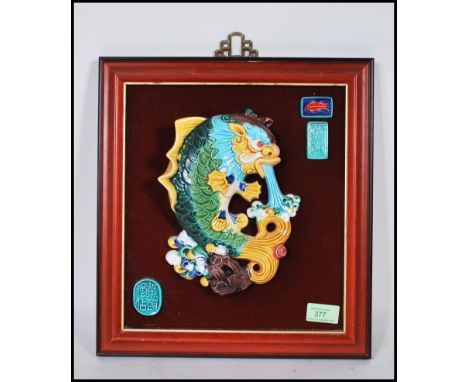 A 20th Century Chinese wall plaque having a raised ceramic hand painted green and yellow koi carp fish symbolising wealth on 