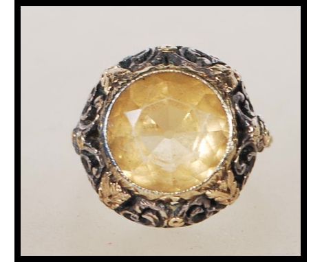 A vintage 18ct yellow gold ring having a central faceted cut oval Citrine set to a decorative pierced floral and scroll mount