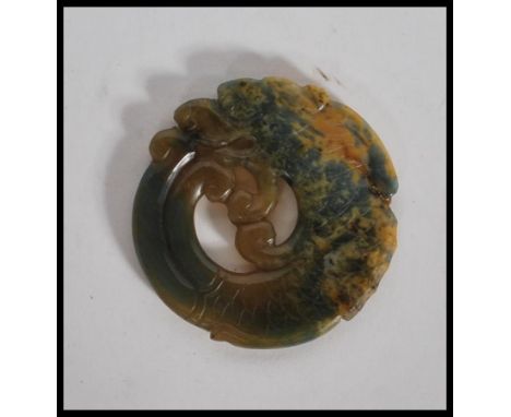 A 20th Century Chinese carved jade pendant medallion in the form of a dragon having carved scale and hair features. Measures 