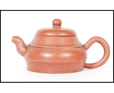 An early 20th Century Chinese Yixing teapot modelled in a brown clay with shaped handle and spout. Character marks to base. M
