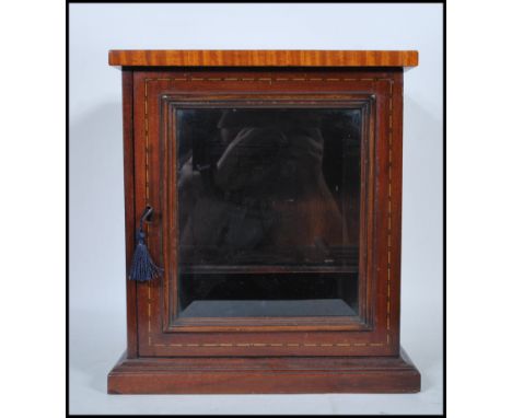 An early 20th Century 1930's mahogany smokers cabinet having satinwood inlaid flared top. The single beveled edged glazed doo