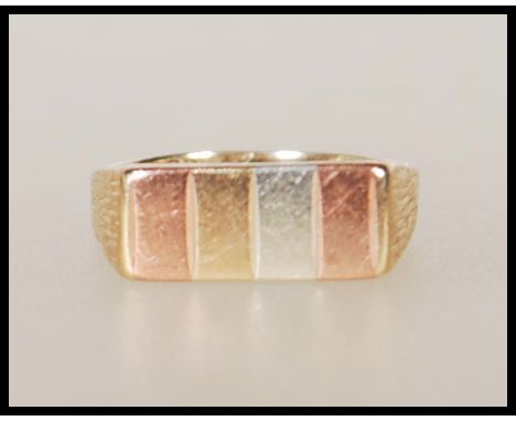 A hallmarked 9ct gold tri colour ring having a rectangular head with four shades of gold and bark effect shoulders. Hallmarke