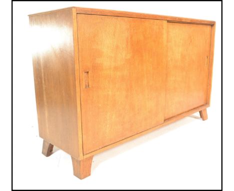 A mid 20th Century 1940's utility light oak sideboard of simple rectangular form having double door sliding door action. The 