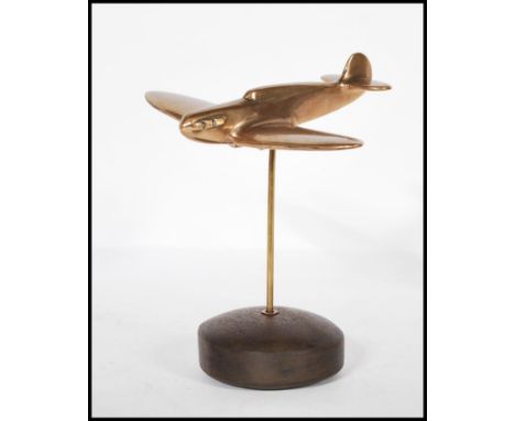 A mid 20th Century vintage trench art style brass desk ornament of a WWII second world war spitfire plane raised on a circula